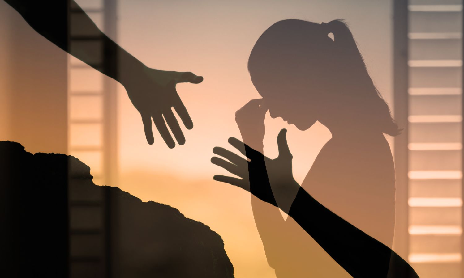 Silhouettes show a person reaching out to another in distress during sunset.